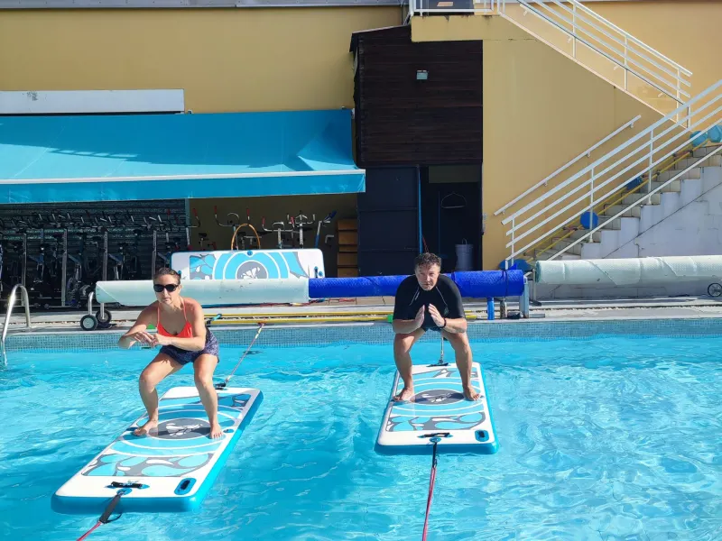 Exercice de gainage sur planche de paddle dans le bassin d’Aqua Forme