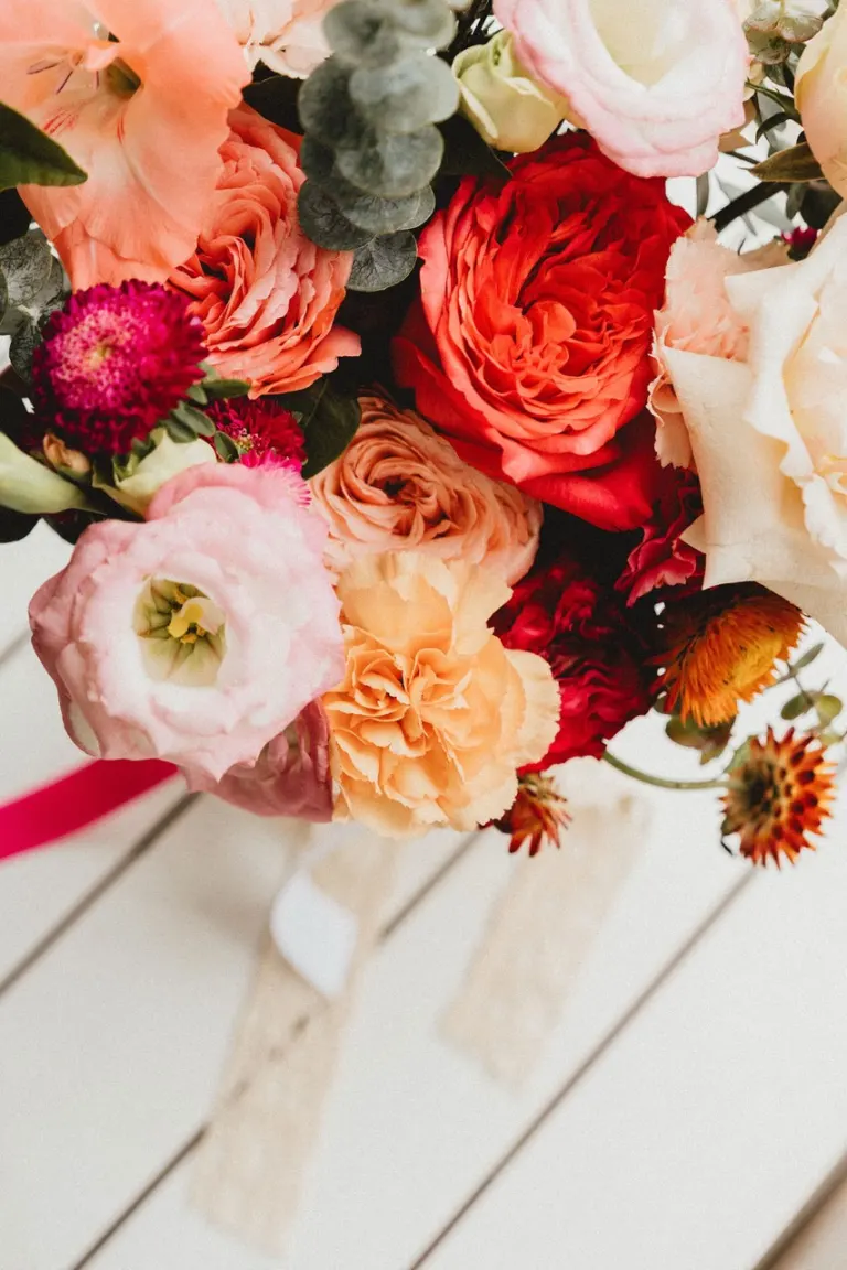 Détail de fleurs aux tons roses et corail dans une composition de mariage