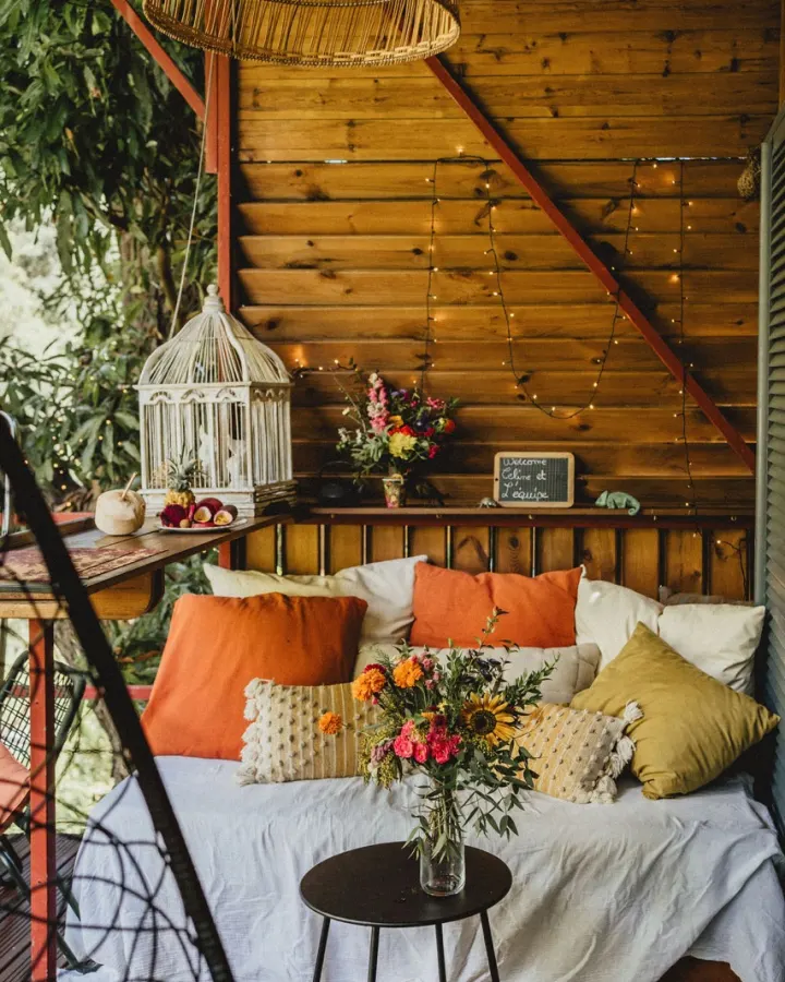Coin salon cosy avec coussins colorés et fleurs, installé dans une case en bois