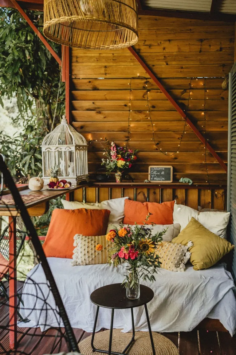 Coin salon cosy avec coussins colorés et fleurs, installé dans une case en bois