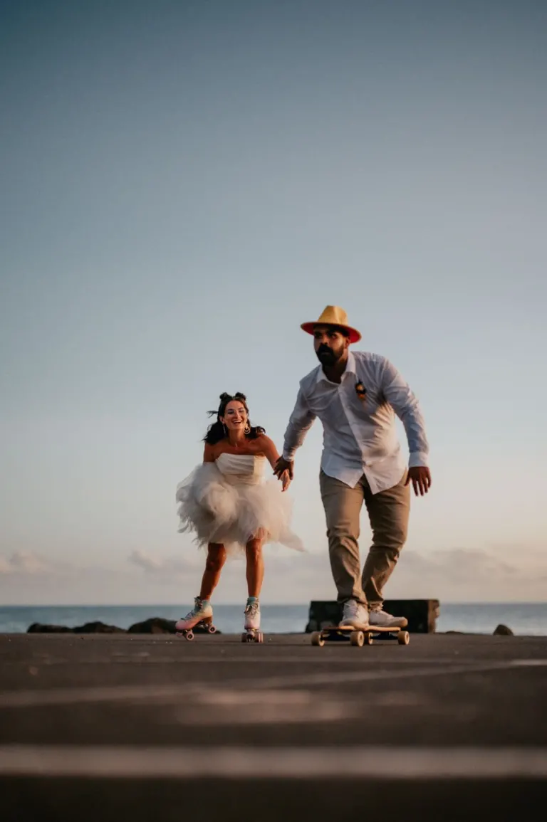 Mariés faisant du skate sur le front de mer en tenue de mariage