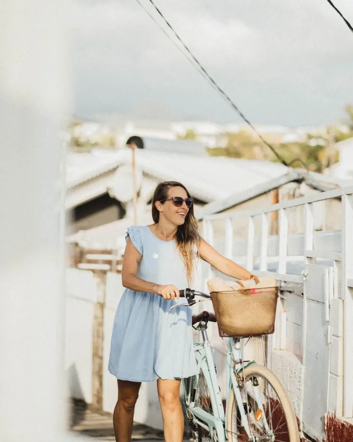 Céline, wedding planner de Green idylle, à vélo devant une case créole blanche