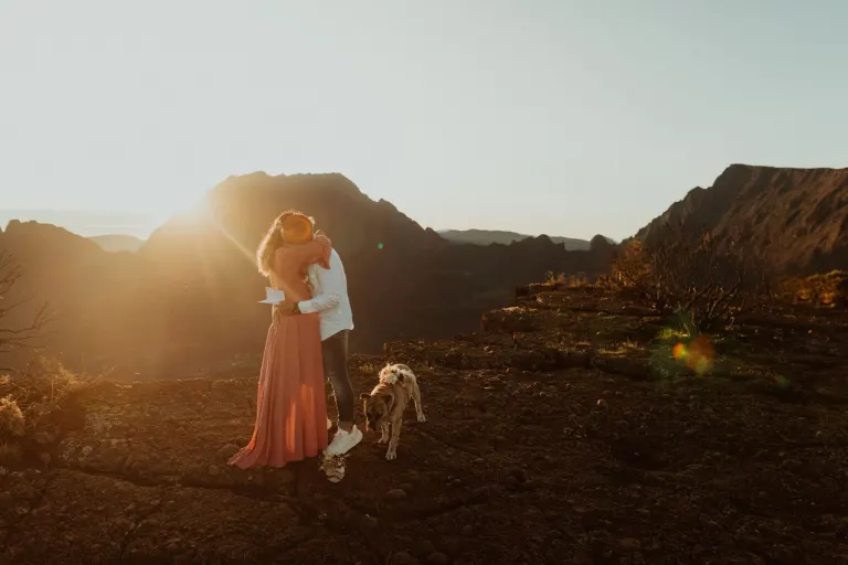 Couple de jeunes mariés et leur chien sur un paysage volcanique au soleil couchant