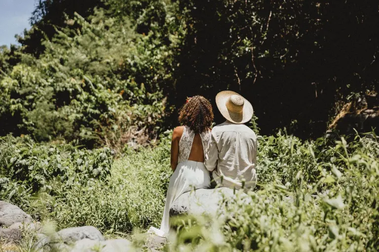 Mariés vus de dos au milieu des herbes hautes, dans un paysage de pleine nature