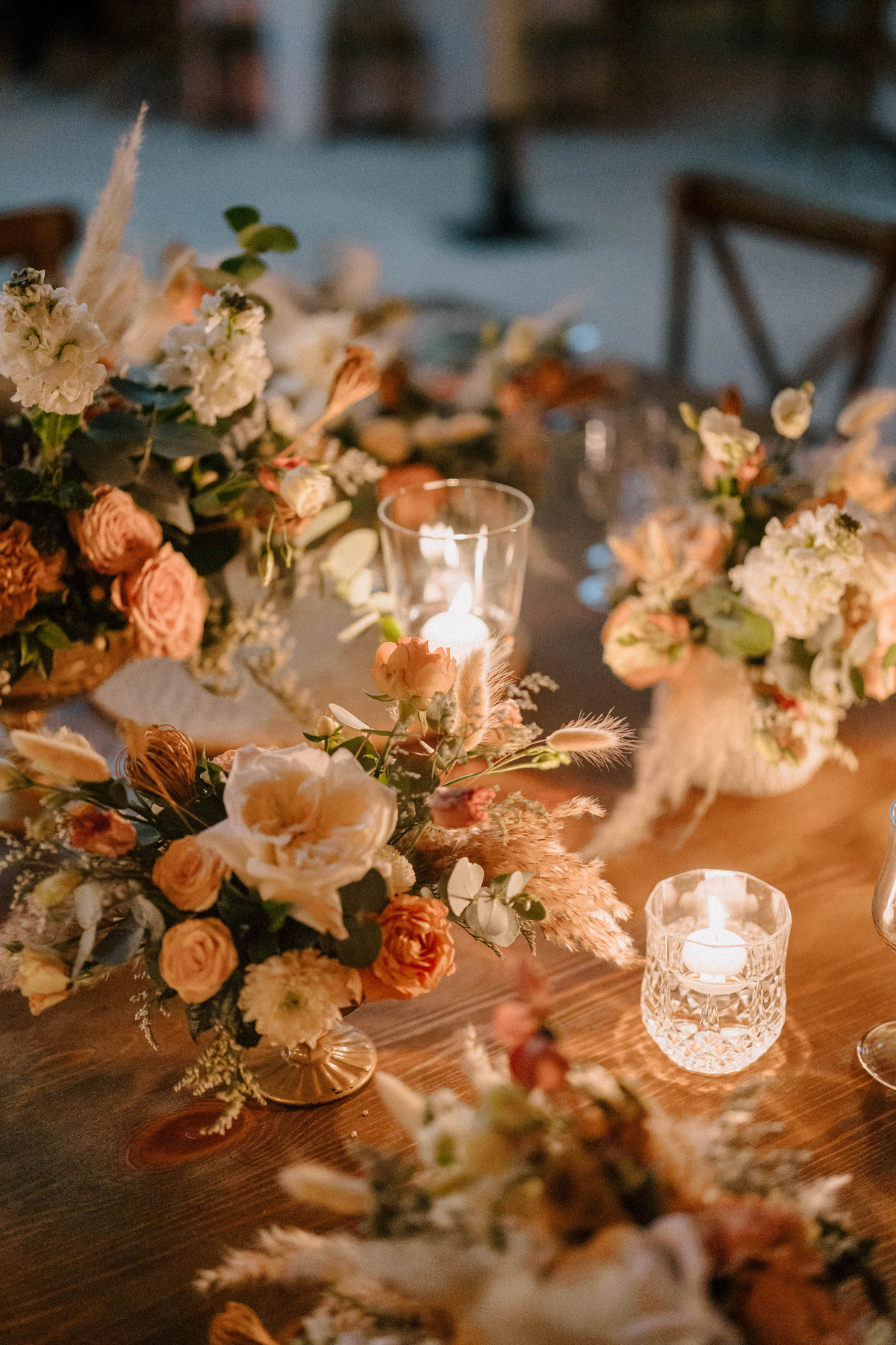 Décoration florale de table aux tons pêche et lumière de bougies