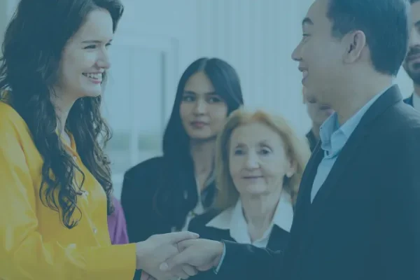 Deux professionnels se serrent la main, entourés de collègues souriants