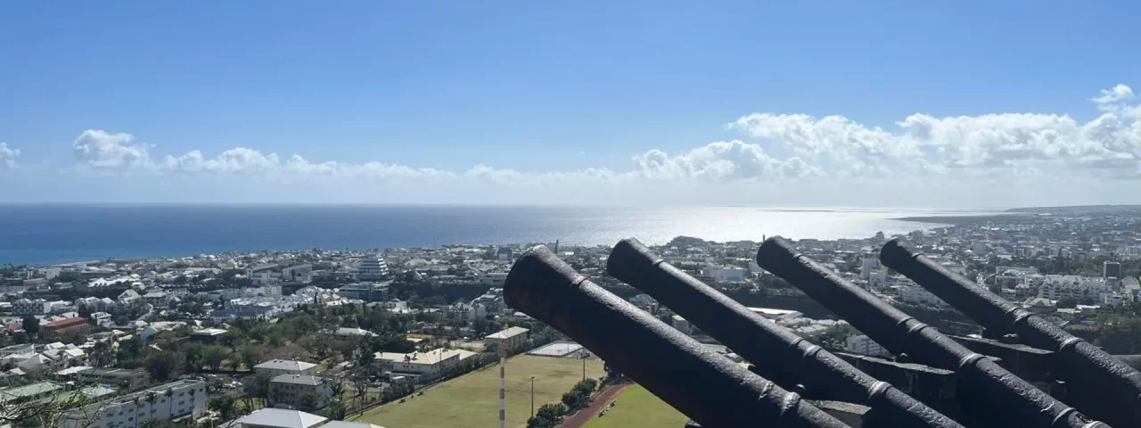 Vue sur Saint-Denis et l’océan Indien depuis les hauteurs, avec d’anciens canons au premier plan