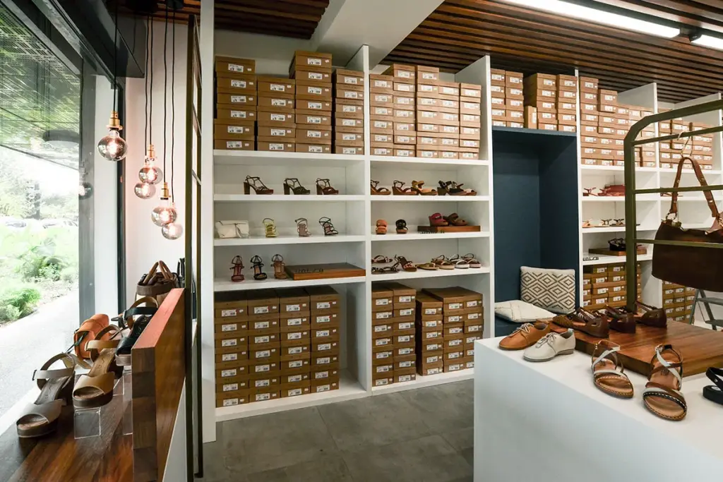 Intérieur de la boutique Chaus’en Folie à L’Ermitage-les-Bains avec rayonnages blancs, niche bleu marine et plafond en lames de bois