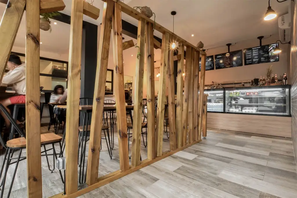 Salle d’un coffee bar à Saint-Denis avec claustra en tasseaux de bois brut, comptoir et vitrines réfrigérées
