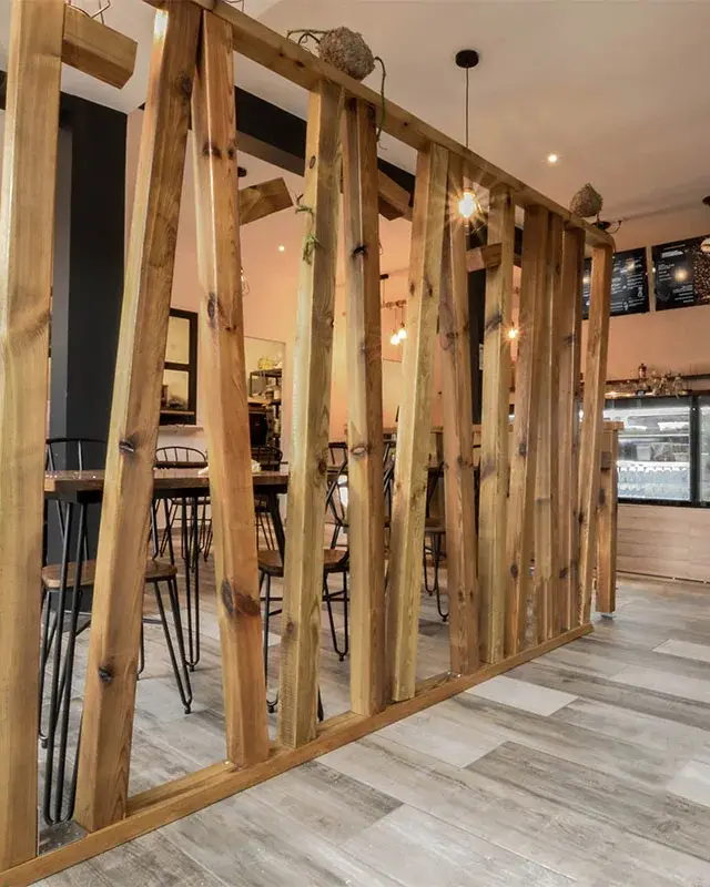 Salle d’un coffee bar à Saint-Denis avec claustra en tasseaux de bois brut, comptoir et vitrines réfrigérées