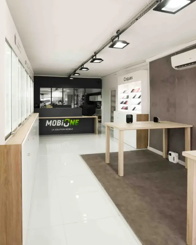 Comptoir noir au logo MobiOne au fond de la boutique, tables de démonstration et mur effet béton