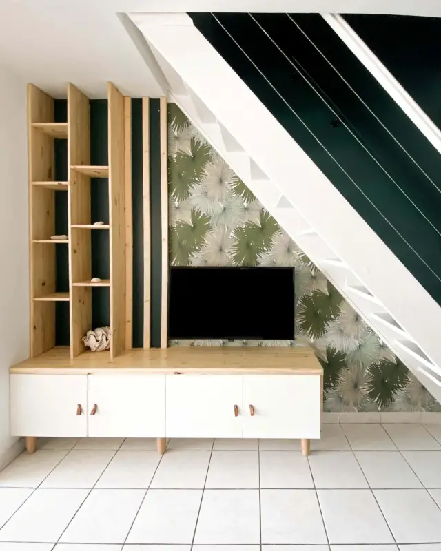 Meuble sur mesure en pin et blanc sous l’escalier, papier peint palmiers et cage d’escalier vert sapin dans un T4 à Saint-Leu