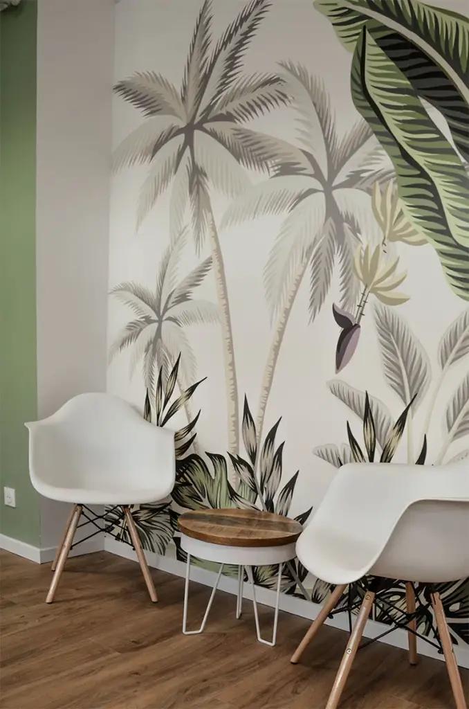 Salle d’attente du cabinet dentaire Les Citadines à Saint-Pierre avec papier peint tropical, fauteuils coques blancs et table basse en bois