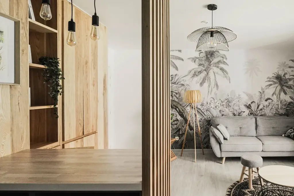 Location saisonnière à Saint-Denis : bibliothèque en bois massif, claustra et salon au papier peint jungle noir et blanc avec lampadaire en bois