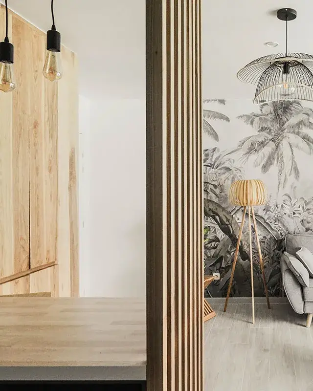 Vue du plan en bois vers le salon à travers un claustra en tasseaux de bois