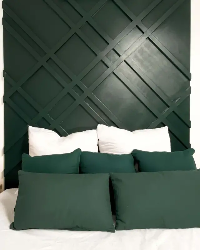 Chambre avec tête de lit vert sapin à lattes croisées, chevets suspendus et lampes cage en bambou