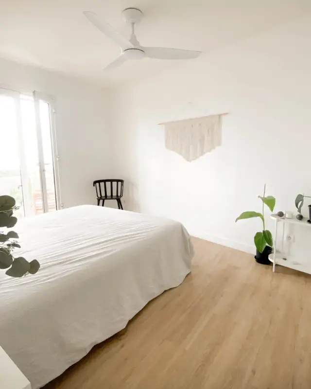 Chambre avec porte-fenêtre sur le balcon, macramé mural, chaise noire et plantes vertes
