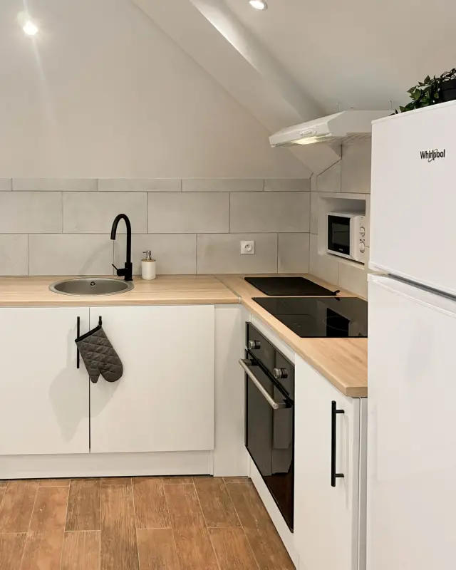 Cuisine en L sous rampant avec plan effet chêne, mitigeur noir mat et niche pour le micro-ondes