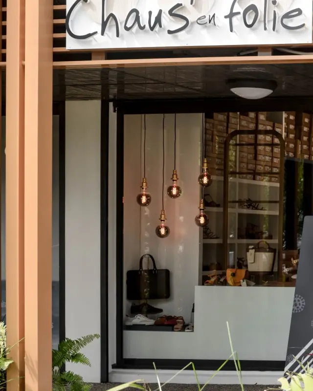 Façade de la boutique Chaus’en Folie avec enseigne, structure en lames de bois et vitrine éclairée
