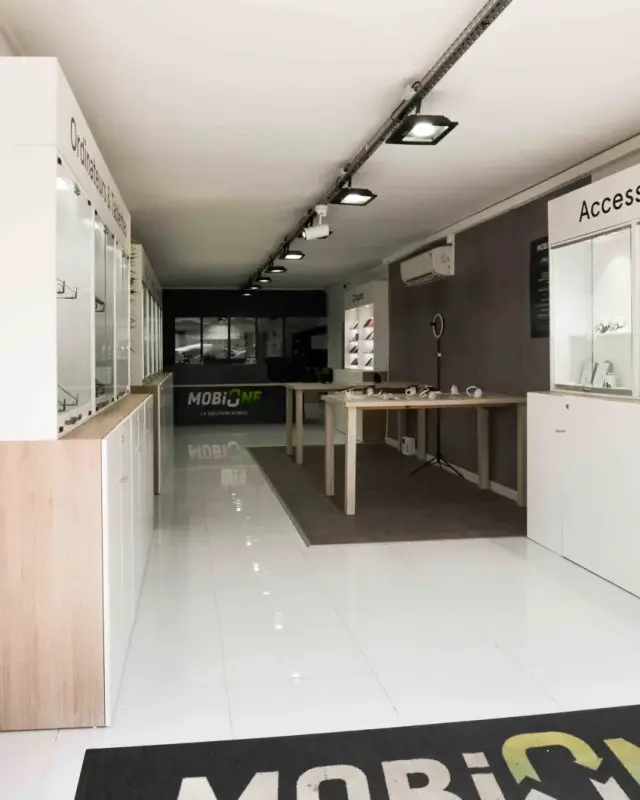 Entrée de la boutique MobiOne avec tapis au logo, vitrines Accessoires et comptoir au fond