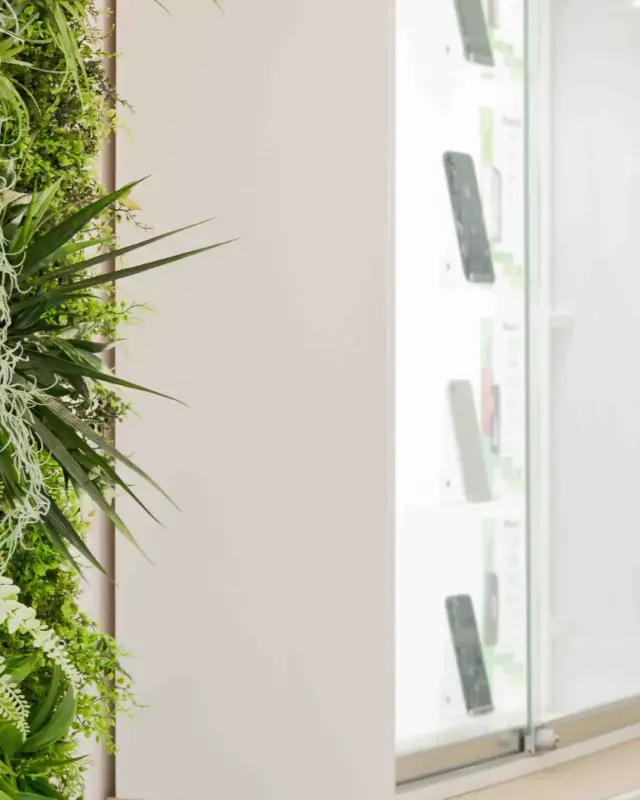 Détail d’un mur végétal à côté d’une vitrine de smartphones