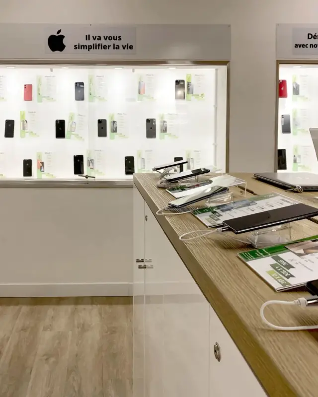 Plateau en chêne de l’îlot avec smartphones, étiquettes de prix et vitrines éclairées en arrière-plan