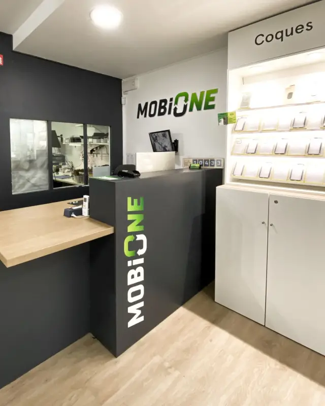 Angle du service après-vente avec comptoir anthracite, tablette en chêne, logo vert en relief et présentoir de coques éclairé