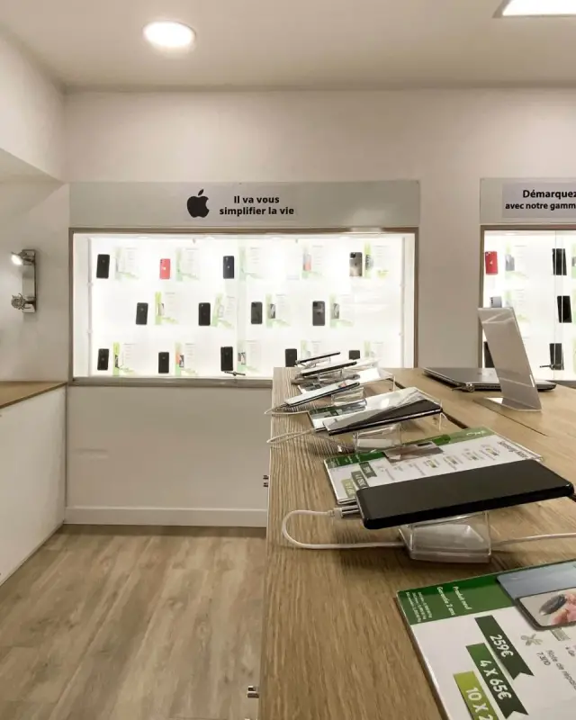 Vitrines murales éclairées de smartphones sous des bandeaux signalétiques et des spots encastrés