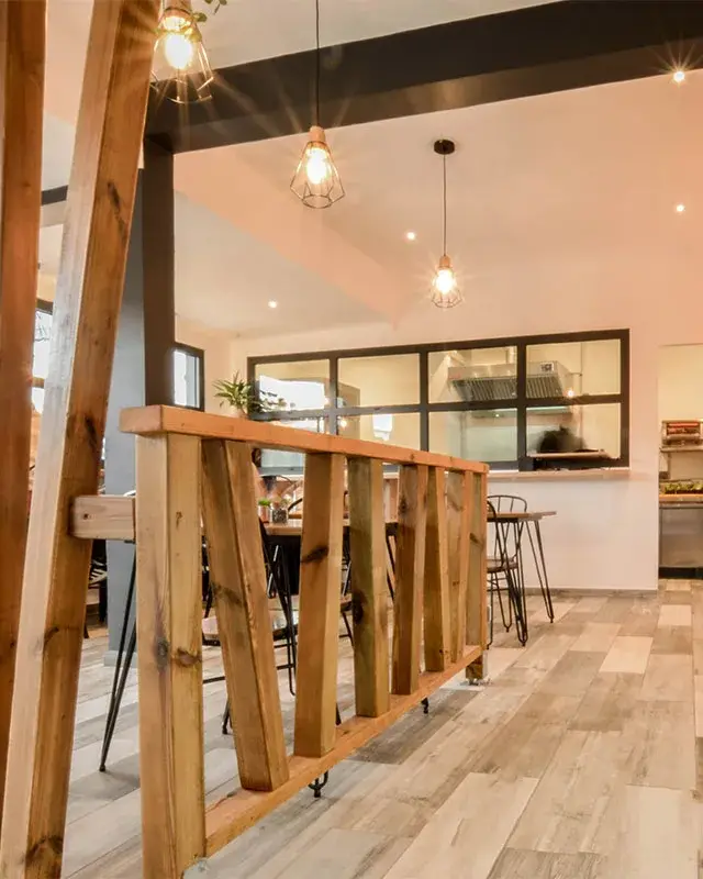 Claustra en bois brut, suspensions cage et verrière noire donnant sur la cuisine