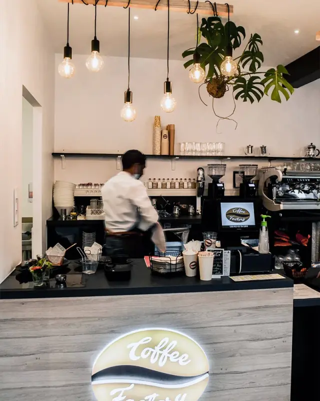 Comptoir habillé de bois gris avec logo rétroéclairé et ampoules à filament suspendues à une poutre