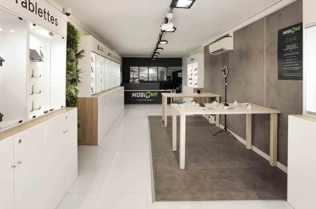 Intérieur de la boutique MobiOne à Saint-Paul avec vitrines éclairées, mur végétal et tables de démonstration en bois clair