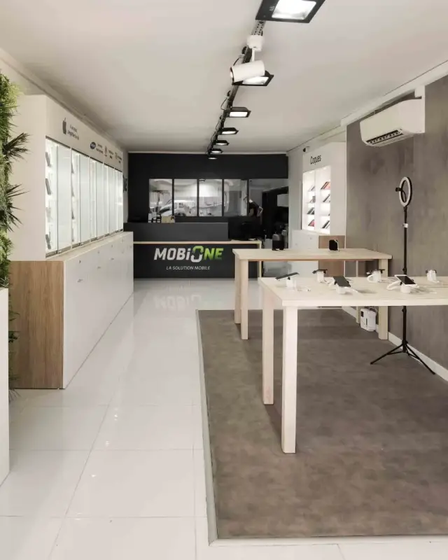 Intérieur de la boutique MobiOne à Saint-Paul avec vitrines éclairées, mur végétal et tables de démonstration en bois clair