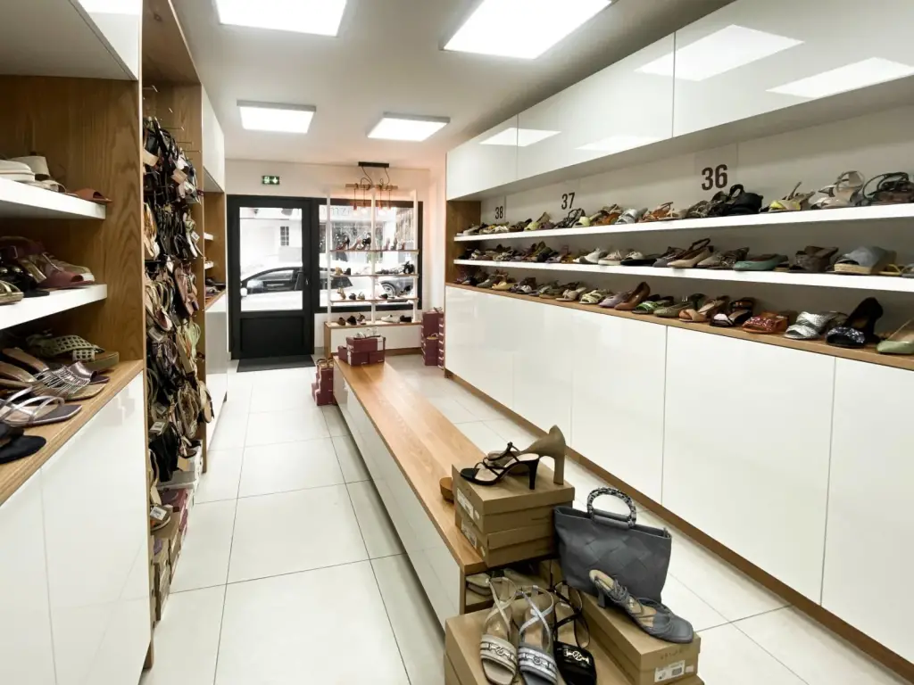 Intérieur de la boutique Chaus’en Folie Outlet à Saint-Denis avec linéaire blanc classé par pointure et banc d’essayage en chêne