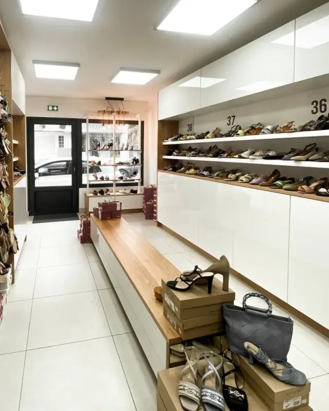 Intérieur de la boutique Chaus’en Folie Outlet à Saint-Denis avec linéaire blanc classé par pointure et banc d’essayage en chêne