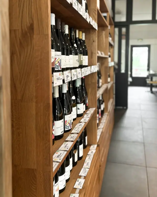 Rayonnage de vins en chêne massif avec étiquettes de prix, allée au carrelage anthracite