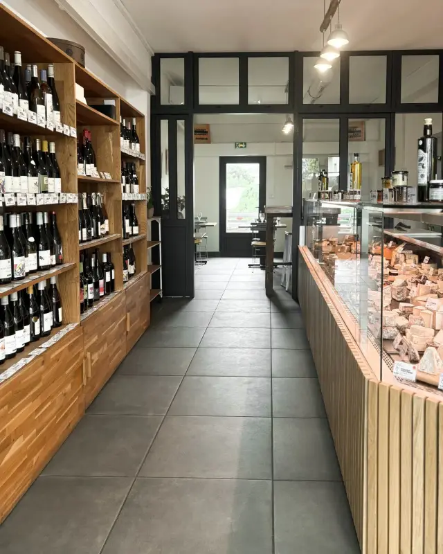 Verrière d’atelier noire donnant sur l’espace de dégustation, suspensions accrochées à une branche de bois flotté