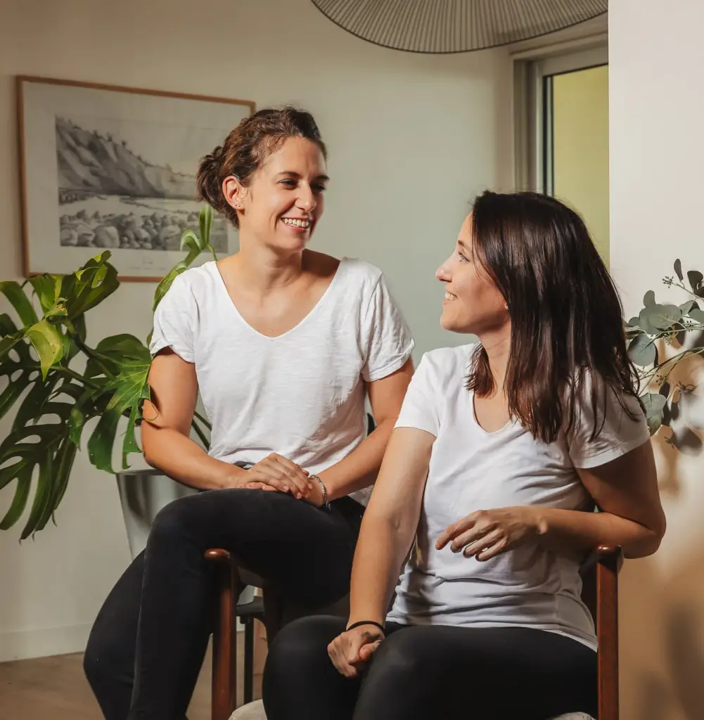 Hermine et Amanda, fondatrices de Décogité, assises côte à côte dans un intérieur décoré de plantes vertes
