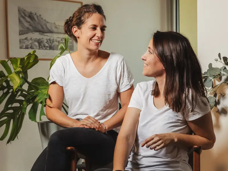 Hermine et Amanda, fondatrices de Décogité, assises côte à côte dans un intérieur décoré de plantes vertes