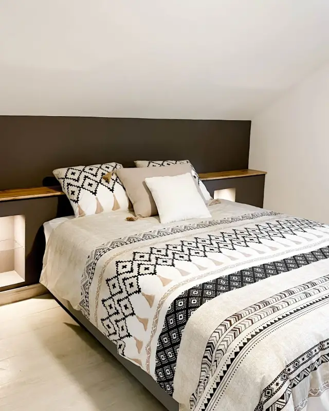 Chambre sous pente avec mur taupe, tablette en chêne et niches éclairées servant de chevets