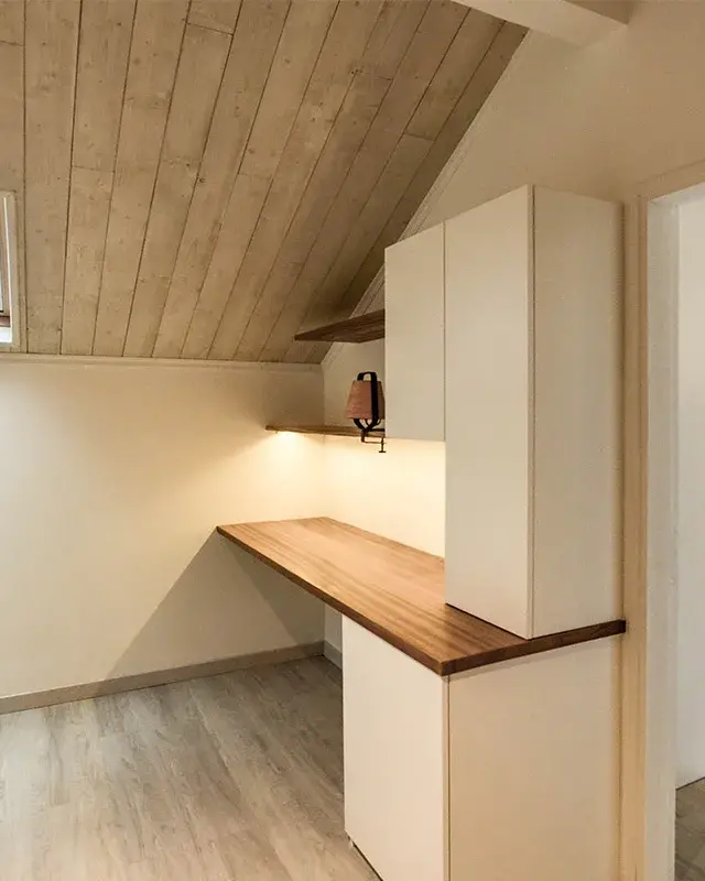 Pièce sous toiture avec lambris, fenêtre de toit et bureau intégré à plateau bois
