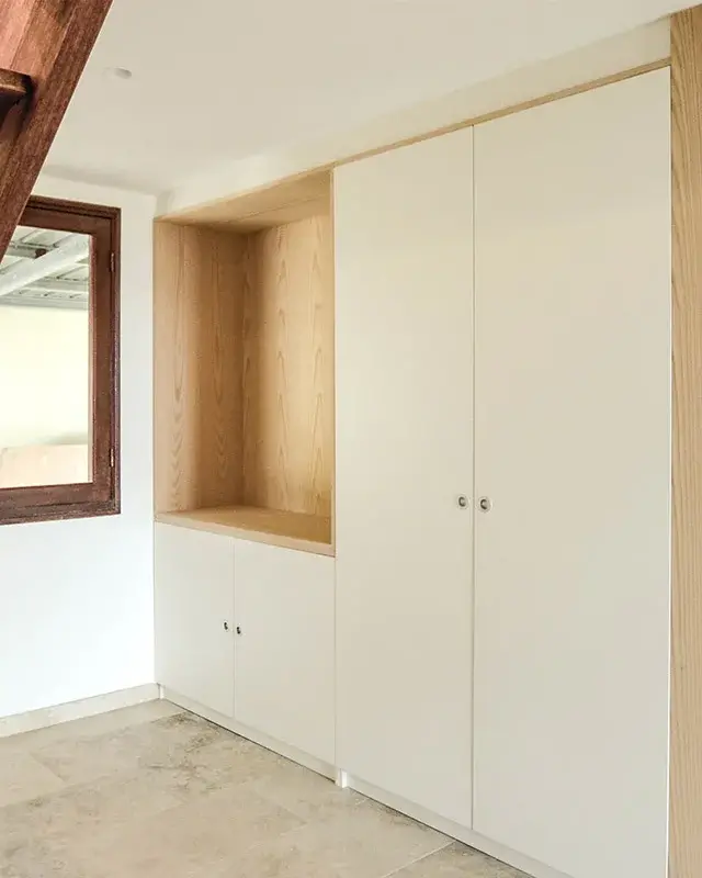Escalier en bois foncé à côté de placards blancs et d’une niche en bois clair