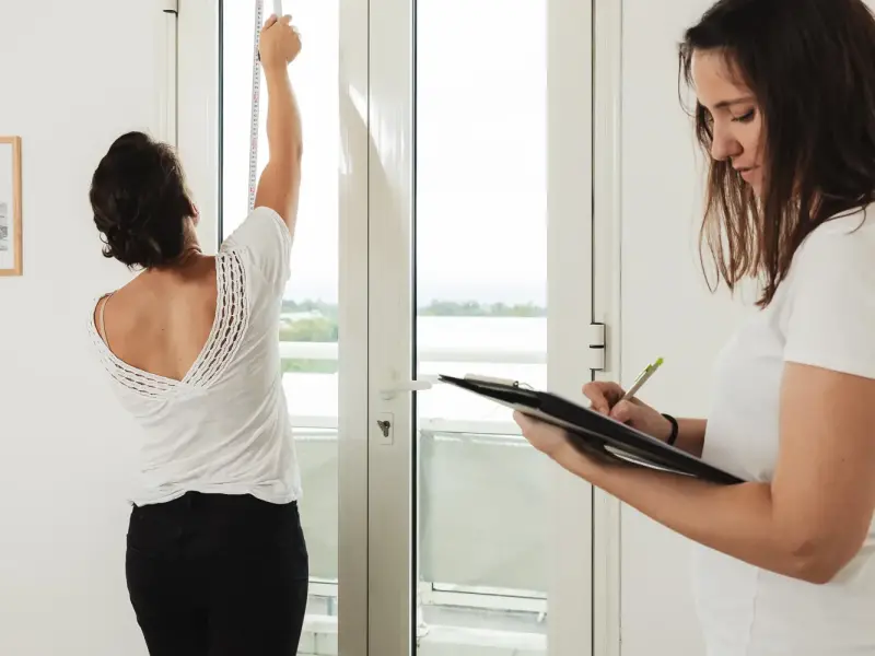 Hermine et Amanda prennent les mesures d’une porte-fenêtre lors d’une visite sur site