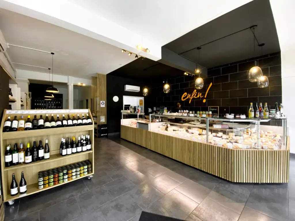 Intérieur de la fromagerie Enfin ! Le Fromager à Saint-Denis avec comptoir en L habillé de tasseaux de chêne et zone noire au logo de l’enseigne