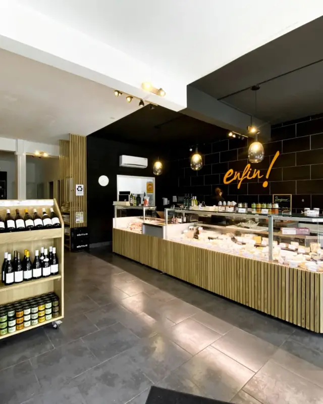 Intérieur de la fromagerie Enfin ! Le Fromager à Saint-Denis avec comptoir en L habillé de tasseaux de chêne et zone noire au logo de l’enseigne