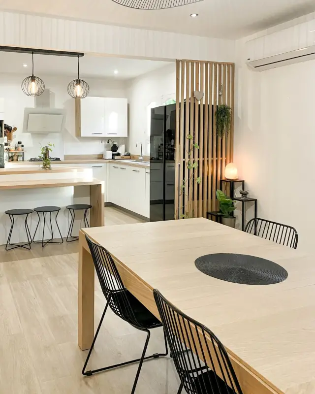 Cuisine ouverte et grande table en bois clair d’une maison familiale rénovée à Saint-Pierre