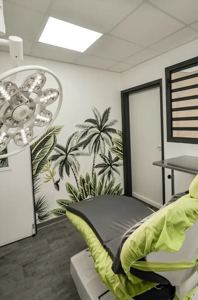 Salle de soins du cabinet dentaire Les Citadines avec fauteuil dentaire, scialytique et papier peint à palmiers