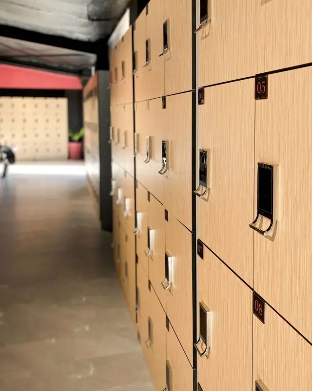 Casiers de vestiaire en stratifié bois clair avec numéros rouges et serrures électroniques