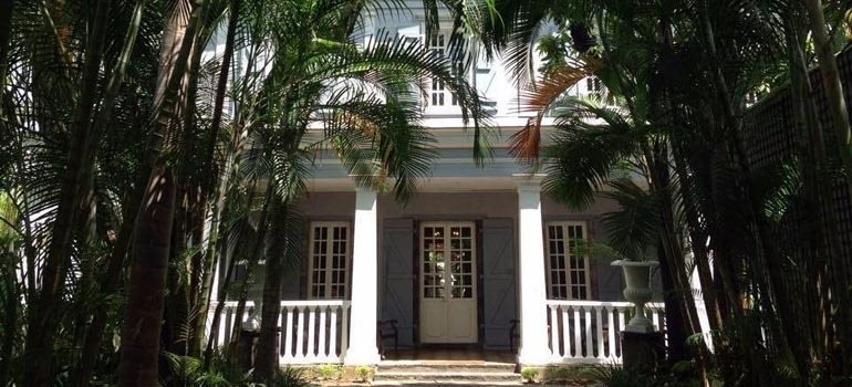 Façade à colonnes d'une maison de maître créole au milieu des palmiers