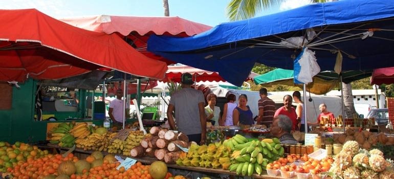 Étals de fruits tropicaux sous les parasols d'un marché forain de l'Ouest
