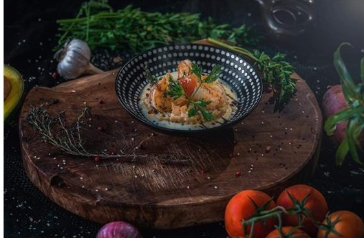 Plat de la mer en sauce aux herbes fraîches, servi sur une planche en bois par le chef Arthur